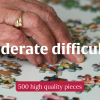 "Moderate difficulty" photo of an elderly woman's hand putting together a jigsaw puzzle.